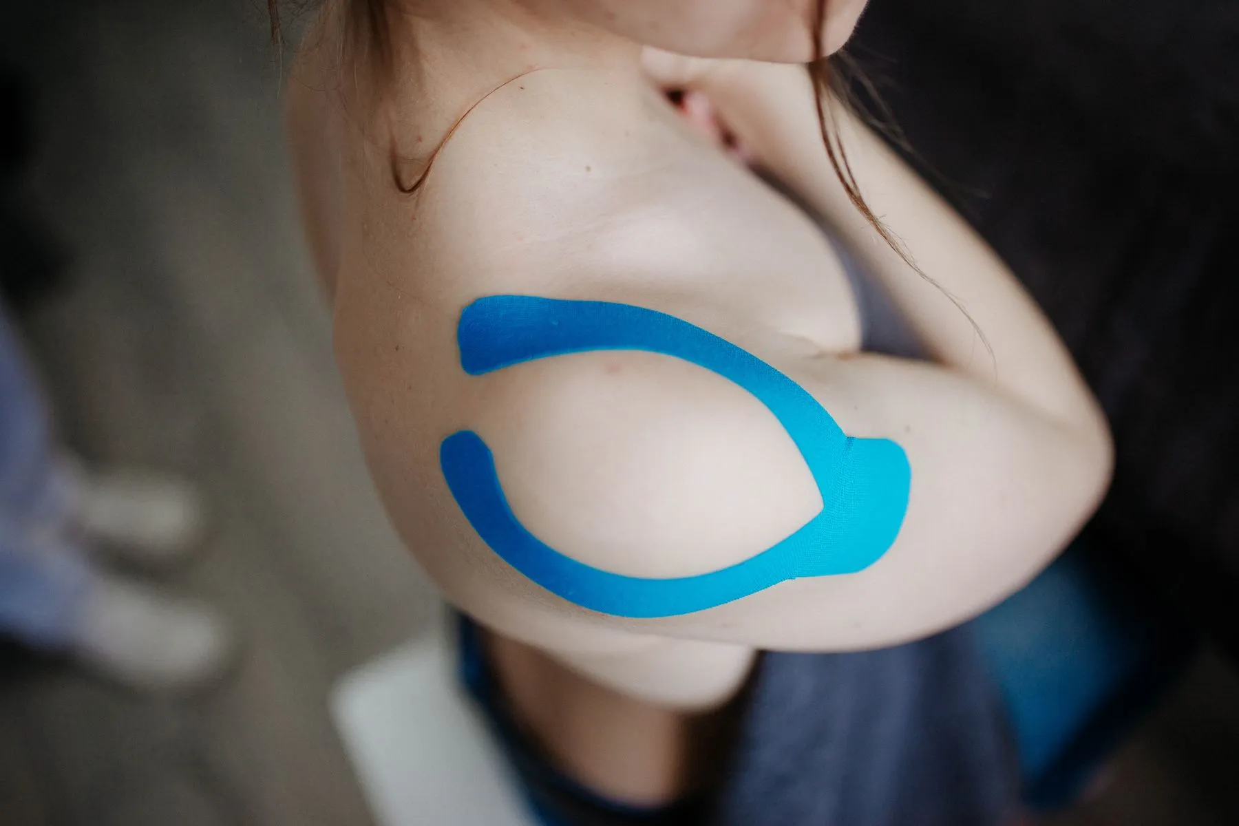 Blaues Kinesio-Tape klebt auf einer Schulter